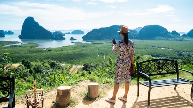 写真 山の頂上から渓谷の景色を楽しんで幸せな若い女性