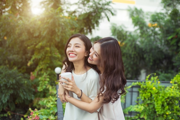 幸せな若い女性の友人が一緒に立っている間、身なりの良い笑顔