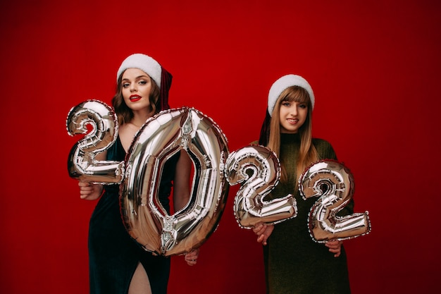 Фото Счастливые молодые женщины с серебряными воздушными шарами 2022 года для празднования рождества и нового года