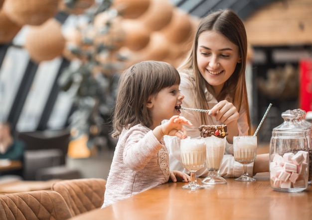 ミルクセーキを飲む子供たちと幸せな若い女性の母