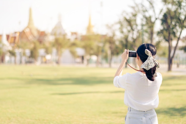 カメラを持った幸せな若者のアジア人女性は、週末の余暇に通りの街を旅します。