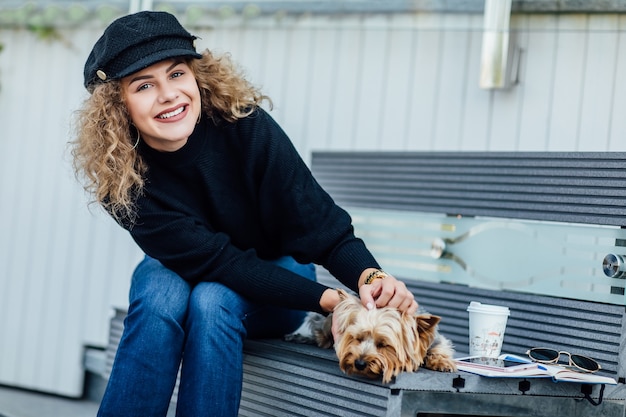 Happypretty womanl houdt haar mooie yorkshire terrier-hond vast terwijl ze op de stadsbank zit.