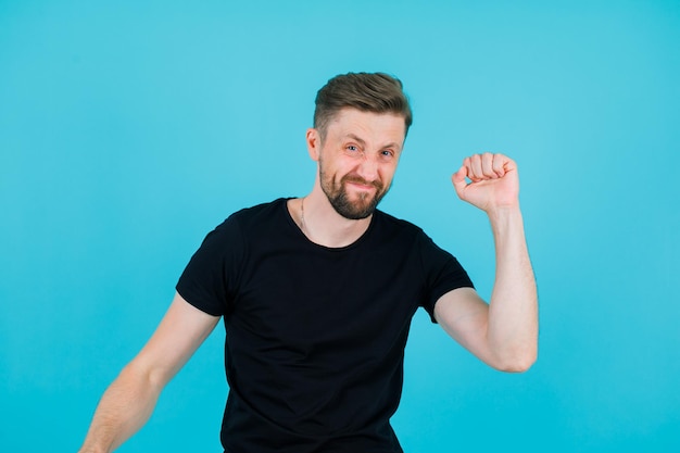 Hapy jonge man steekt zijn vuist op blauwe achtergrond