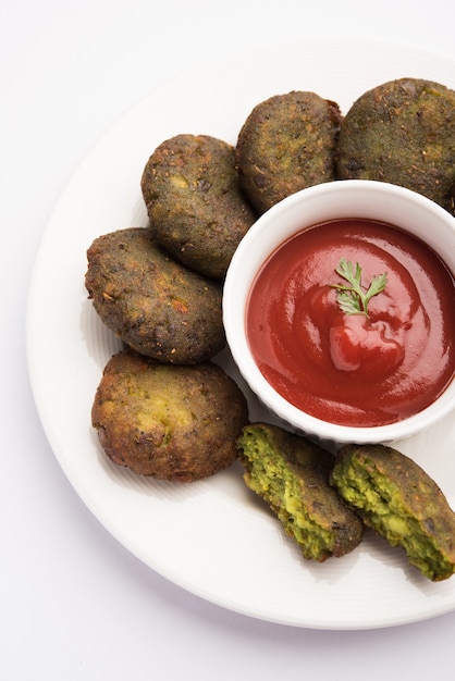 Hara Bhara Kabab or Green Peas Pakora, Popular indian starter food served in a plate with Tomato and Mint Chutney over moody background. Selective focus