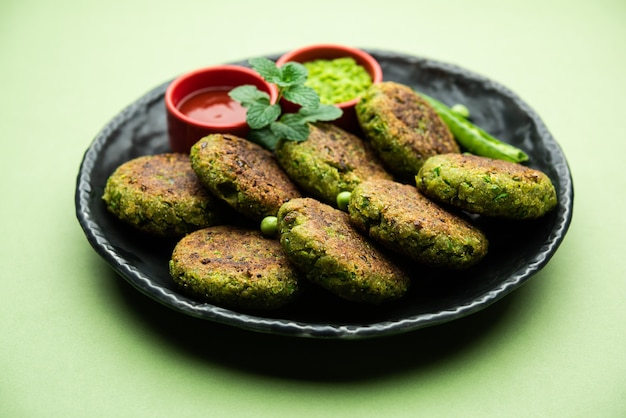 Hara bhara Kabab 또는 Kebab은 변덕스러운 표면 위에 그린 민트 처트니와 함께 제공되는 인도 채식 스낵 레시피입니다. 선택적 초점