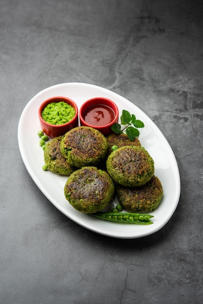 Hara bhara kabab or kebab is indian vegetarian snack recipe\
served with green mint chutney over moody surface. selective\
focus