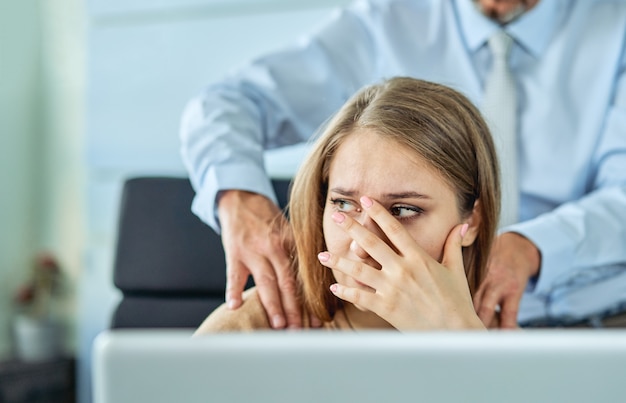 Harassment with a boss touching the arm to his secretary who is sitting in his workplace at office