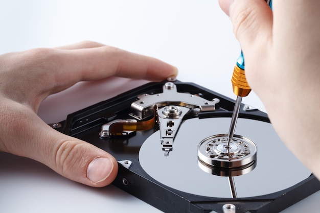 Photo hard disc drive disassembling close up. repairman opening hdd for recovery information, service center and electronics repair concept