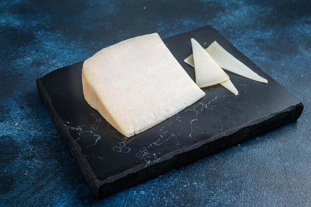 Hard goat cheese on marble board Blue background Top view