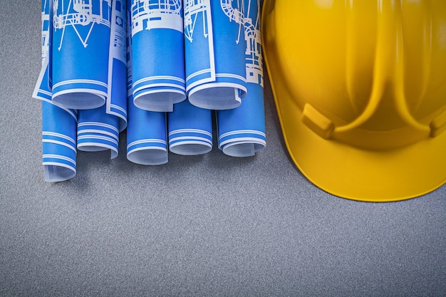 Hard hat blue rolled construction plans on grey background