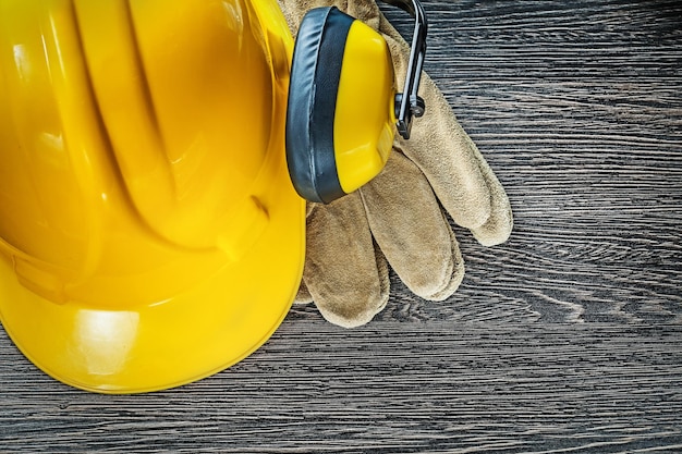 Hard hat earmuffs leather safety gloves on wooden board