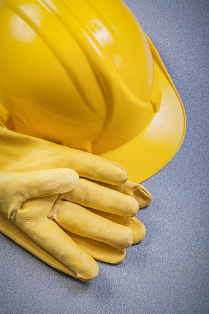 Hard hat pair of leather protective gloves on grey background construction concept