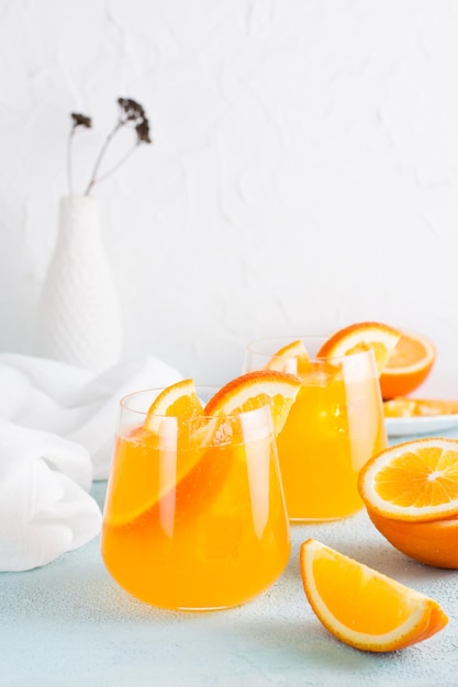 Фото Хард-селтер освежающий апельсиновый коктейль в бокалах на столе домашний напиток вертикальный вид