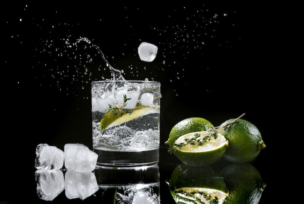 Hard seltzer with lime on a dark wooden background ice cubes fall into a glass with an alcoholic beverage hard seltzer splashes of drink