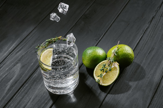 Hard seltzer with lime on a dark wooden background ice cubes fall into a glass with an alcoholic drink hard seltzer