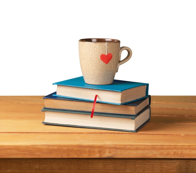 Hardcover books and cup with heart shape on wooden table