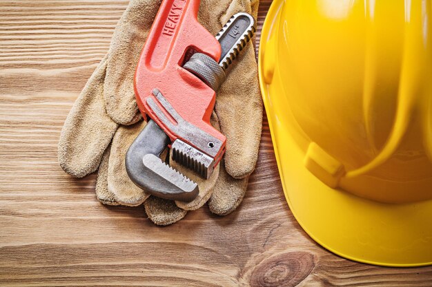 Harde hoed lederen beschermende handschoenen pijpsleutel op houten plank bouwconcept