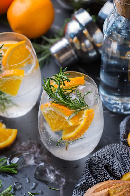 Harde seltzercocktail met sinaasappel, rozemarijn en ijs op een lijst. Zomer verfrissende drank, drankje op een zwarte tafel