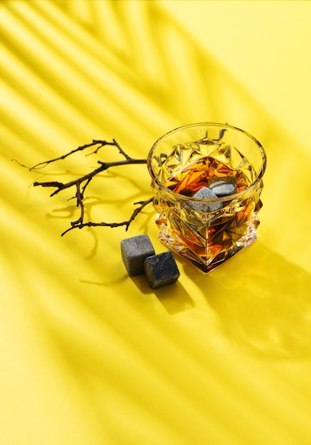 Harde sterke alcoholische dranken in glas: cognac, tequila, scotch, cognac of whisky op een gele achtergrond met harde lichten en schaduwen, bovenaanzicht