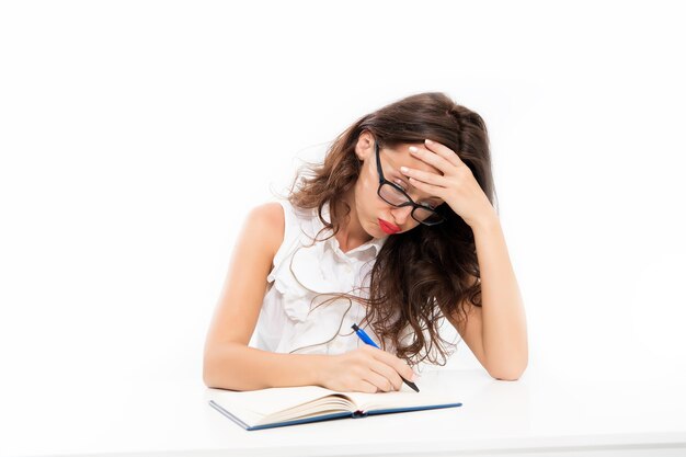 Harde werkdag. leerling druk aan het werk. terug naar school. geconcentreerd op les of examen. vrouw schrijft een essay. Noteer belangrijke informatie. Grote hoeveelheid werk. Drukke overwerkte vrouw zit aan tafel.