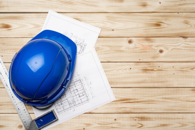 Hardhat and blueprints of architect on wooden top view