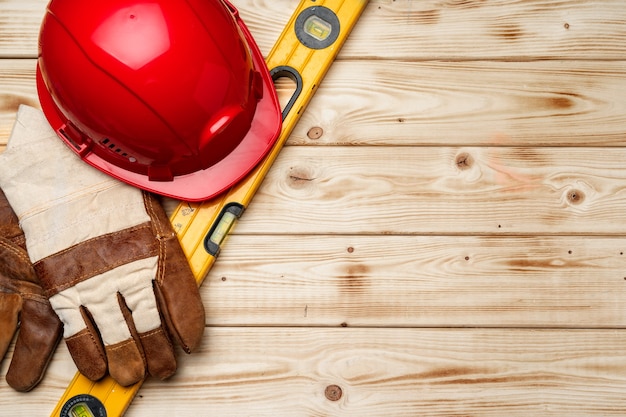 Hardhat and gloves of construction worker on wooden surface top view