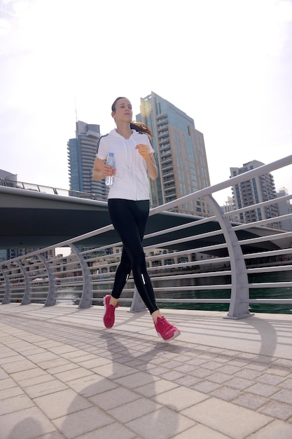 Hardlopen in het stadspark. Vrouwenloper buiten joggen 's ochtends met de stedelijke scène van Dubai op de achtergrond