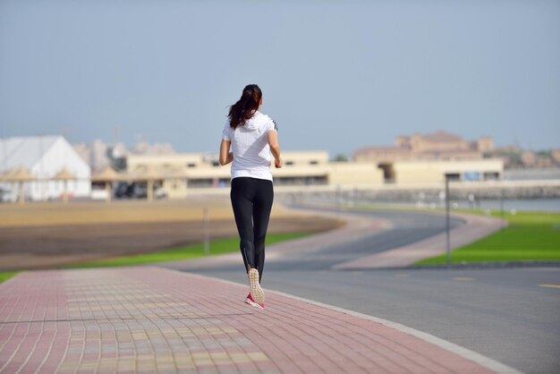 Hardlopen in het stadspark. Vrouwenloper buiten joggen 's ochtends met de stedelijke scène van Dubai op de achtergrond