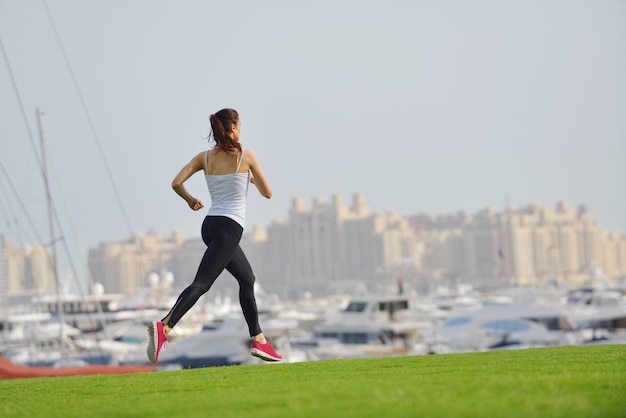 Hardlopen in het stadspark. Vrouwenloper buiten joggen 's ochtends met de stedelijke scène van Dubai op de achtergrond