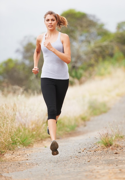 Hardlopen voor fitness een jonge vrouw die op een onverharde weg rent