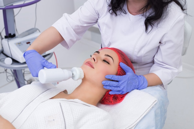 Hardware cosmetology. Beautician performs a mechanical procedure of surface peeling. Brush skin cleaning.