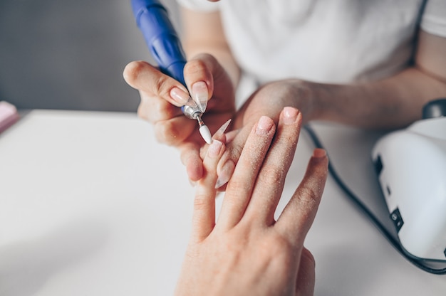 Hardware professioneel manicureproces, nagels reinigen met een frees. Sluit wijfje indienen omhoog schoonheidssalon. Vingernagelbehandeling, maakproces. Elektrische nagelvijlboor in actie