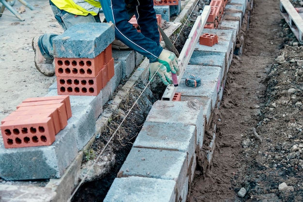 Hardwerkende metselaar die betonblokken legt op een betonnen fundering op een nieuwe huisvestingslocatie