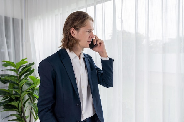 Hardwerkende zakenman staat in een modern kantoor en praat via de telefoon Entiteit