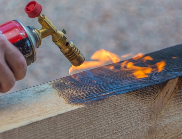 Hardwood timber is treated with fire from a gas burner.