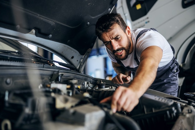 Трудолюбивый преданный бородатый сотрудник в спецодежде ремонта автомобиля
