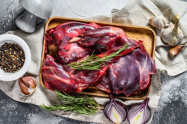 Photo hare meat. raw fresh  wild hare on a wooden table with vegetables and spices