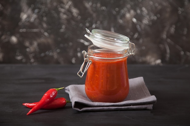 Harissa spicy condiment in a glass jar with a lid and chili.