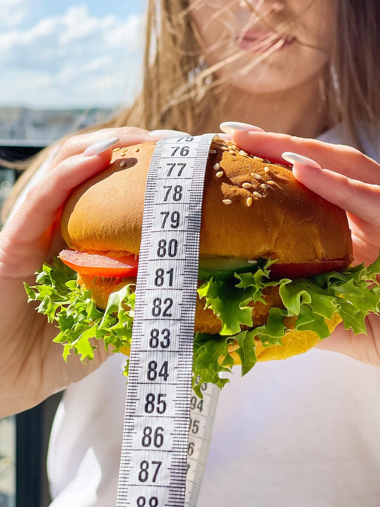 Photo harmful fatty burger with a measuring tape concept diet