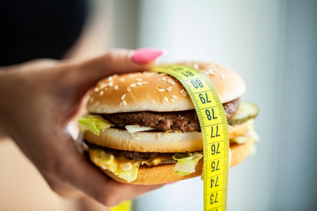 Harmful food. The choice between malicious food and sport. Beautiful young girl on a diet. The concept of beauty and health.