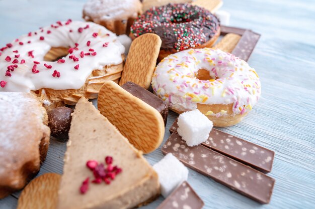 Harmful sweet foods on blue wooden background