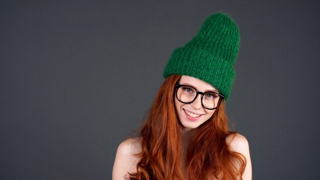 녹색 모자를 쓰고 빨간 머리를 가진 여자를 카메라에 미소