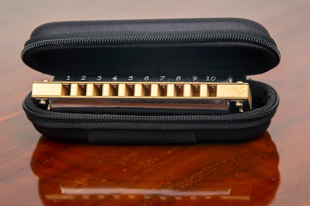 Harmonica in a case on a wooden background. Classical musical wind instrument.