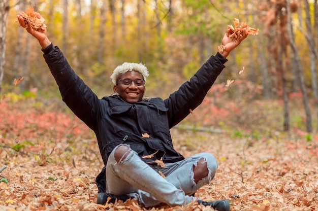 Harmonie met het natuurconcept jonge Afro-Amerikaanse man die mediteert in het herfstpark dat buiten is opgegroeid