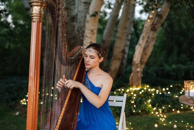 Harpist playing an old harp in the garden