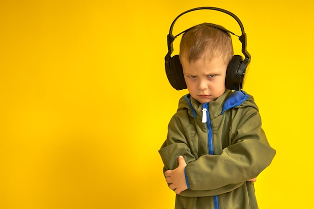Harsh kid in wireless headphones on a yellow background