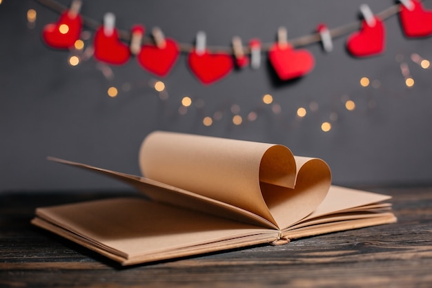 Hart gemaakt van boekbladen in licht, liefde en valentijn concept op een houten tafel