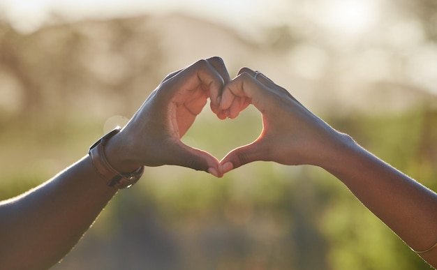 Hart liefde handen en zwart paar in de natuur op vakantiereis of vakantie Romantiek genegenheid emoji en man en vrouw met teken of gebaar voor ondersteuning van vertrouwen en zorg buitenshuis samen op een date