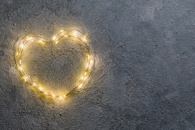 Foto hart van gloeiende garland op donkere reliëf achtergrond. bovenaanzicht en kopieer ruimte. conceptuele achtergrond. valentine dag groet concept