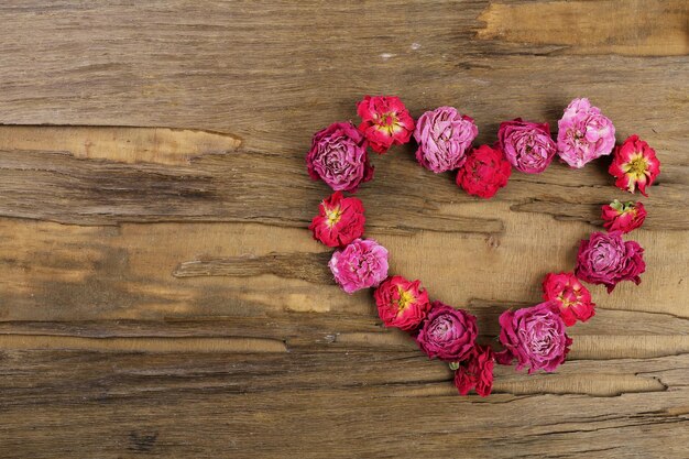 Hart van mooie droge bloemen op houten achtergrond